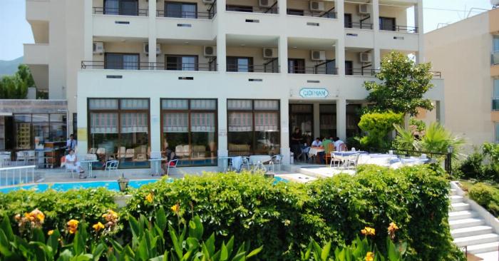 İzmir'de bir otelin şık ve sakin kapalı yüzme havuzu, büyük pencerelerden doğal ışık alıyor ve dinlenmek için şezlonglar bulunuyor.