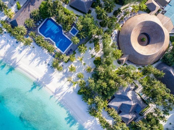 Meeru Island Spa Resort'un berrak sularında renkli mercan resifleri arasında şnorkelle yüzen bir çift