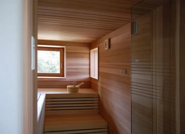 Modern tasarımlı, cam kapılı, aydınlatmalı lüks bir ev saunasının profesyonel imalat sonrası görünümü.