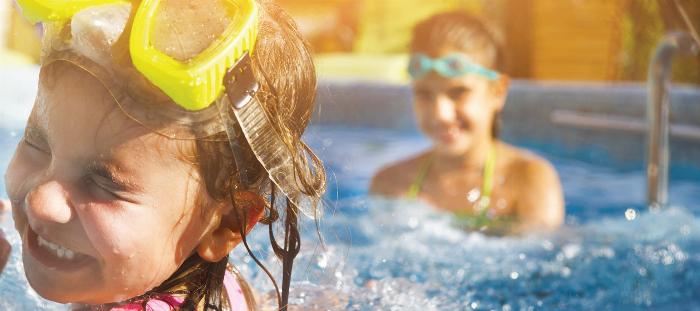 Sauna kovası ve kepçesinin yanında duran farklı sauna yağı şişeleri, buharlı ve ahşap sauna ortamında rahatlatıcı bir atmosfer yaratıyor.